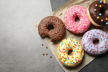 Delicious glazed donuts on grey table, top view. Space for text