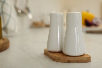 Ceramic salt and pepper shakers on white countertop in kitchen, space for text