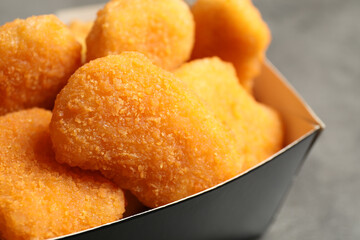 Tasty fried chicken nuggets on grey table, closeup