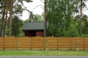 Fototapeta na wymiar Modern building with green roof behind wooden fence on spring day