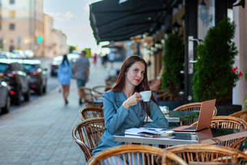 Beautiful professional ht manager woman in a fashion business suit working on a laptop and drinking coffee