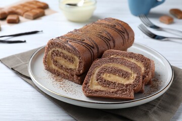 Tasty chocolate cake roll with cream on white wooden table, closeup