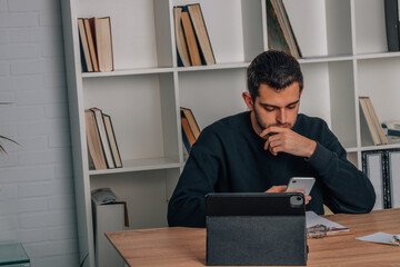 young man at home with mobile phone and laptop