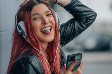 carefree redhead girl with mobile phone and headphones