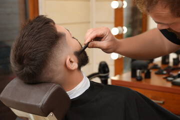 Professional hairdresser working with client in barbershop, closeup