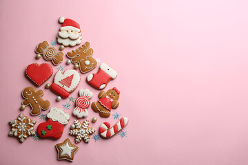 Obraz premium Delicious gingerbread cookies arranged in shape of Christmas tree on pink background, flat lay. Space for text