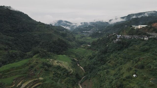 forward drone motion of mountains and rice terraces in ifugao province philippines with clouds and river