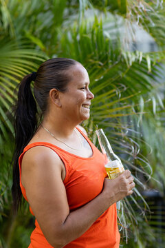 aboriginal woman with long hair in profile holding a bottle of beer