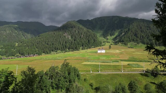 General plan of small church in green field, windy day in Swiss mountains