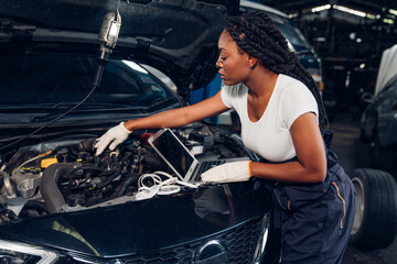 Woman auto mechanic using laptop for checking and repair maintenance auto engine is problems at car...