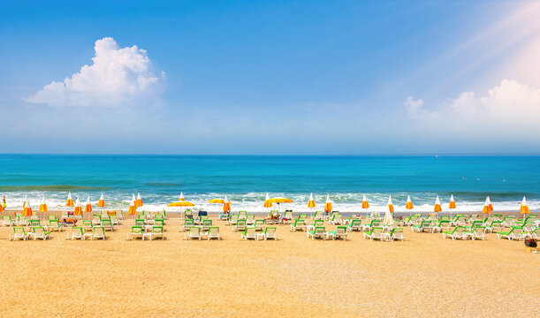 Beautiful image of  Mediterranean golden beach with blue skies, white clouds, expanse of turquoise sea, sun loungers and umbrellas.