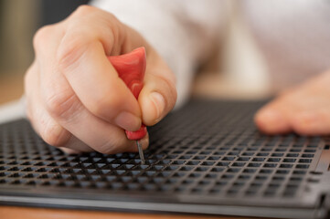 A woman uses a special stencil and stylus to write a letter in braille. 