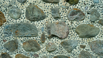 Old boulder house wall. Stones of different colors and sizes