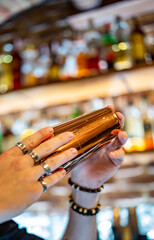 Fototapeta man at bar holds steel shaker in her hands, shakes it to make cocktail. obraz