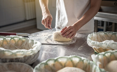 Baker cuts the dough with a knife before going into the oven for baking. Production of bakery products