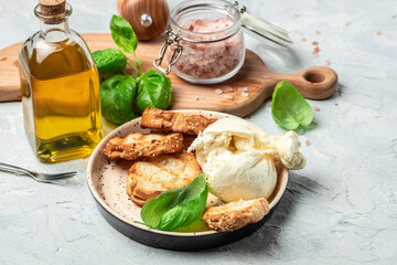 fresh handmade soft Italian cheese from Puglia, white balls of burrata or burratina cheese Basil and Olive Oil and Ciabatta. place for text, top view