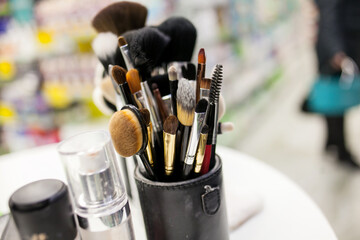 Makeup brushes of different sizes in a black leather tube on a white table. close-up of makeup...