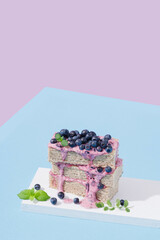 waffle cake with blueberries and mint on a blue and purple background. Hard light.
