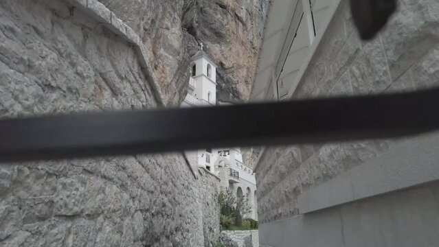 Ostrog monastery in Montenegro seen from the gap in the iron fence. The unique monastery in the rock. the Monastery of Ostrog dedicated to Saint Basil of Ostrog. 4K videos.