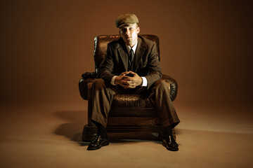 Cinematic portrait of young man, retro 1920s style english gangster wearing suit and cap isolated...