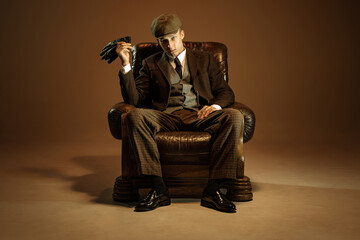 Cinematic portrait of young man, retro 1920s style english gangster wearing suit and cap isolated...