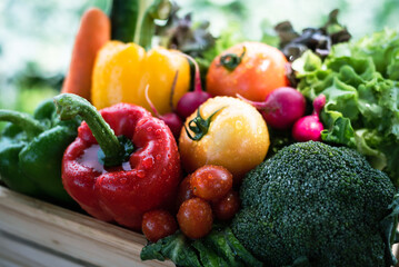 Crate filled with a large selection of healthy fresh organic fruits and vegetables shot on dark wooden table.