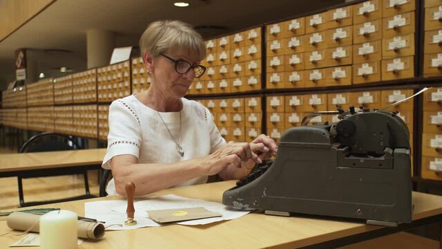 4K. An elderly woman typing on a typewriter in the library