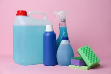 Bottles of different detergents and tools on pink background. Cleaning supplies