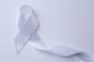 White awareness ribbon on white background, top view