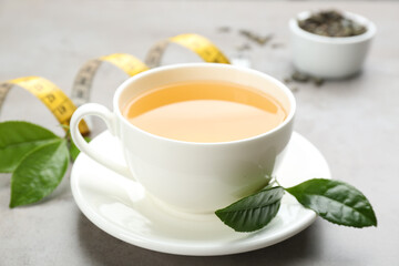 Cup of herbal diet tea and measuring tape on light table