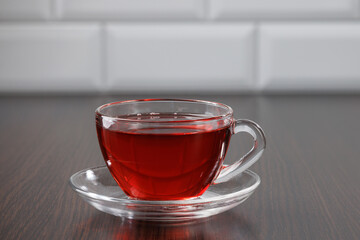 Glass cup with hot tea on the background of the table and white ceramic tiles. Selective focus.