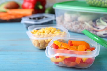 Set of plastic containers with fresh food on light blue wooden table, space for text