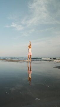 Woman stretching and relaxing on the seashore at the beach. Freedom, mindfulness and meditation concept.