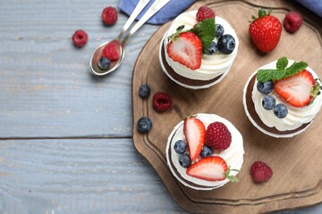 Sweet cupcakes with fresh berries on wooden table, flat lay. Space for text