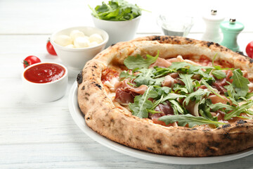 Tasty pizza with meat and arugula on white wooden table, closeup