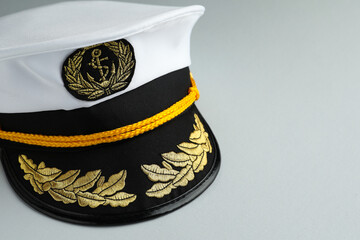 Peaked cap with accessories on light grey background, closeup. Space for text