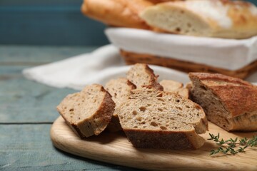 Cut buckwheat baguette with thyme on light blue wooden table, closeup