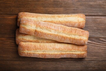 Tasty baguettes on wooden table, top view