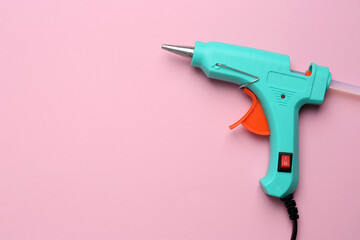 Fototapeta Turquoise glue gun with stick on pink background, top view. Space for text obraz