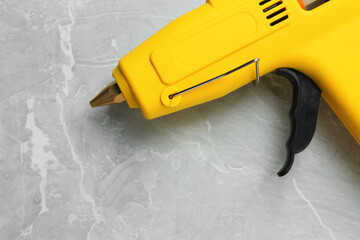 Fototapeta Yellow glue gun on light grey marble table, above view obraz