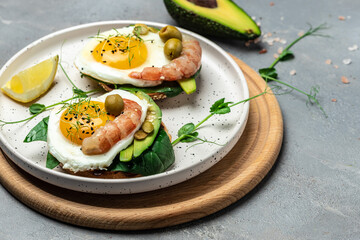 shrimps, prawns, soft fried egg, fresh salad, tomatoes, cucumbers and avocado on a light background. Ketogenic diet breakfast. Keto, paleo lunch. Top view