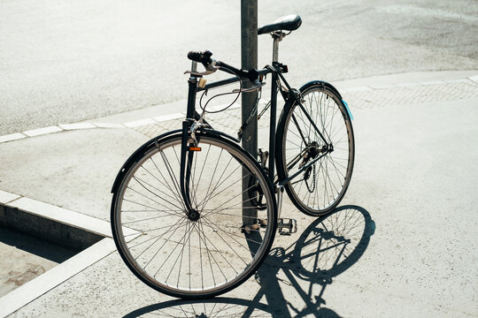 A photo of a bicycle leaning against a pole outside