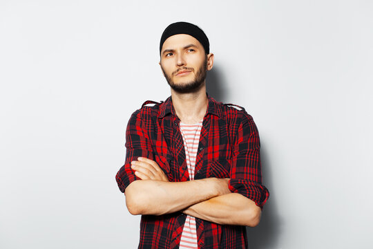 Studio portrait of young handsome guy, with crossed arms. Wearing red plaid shirt and black headband.