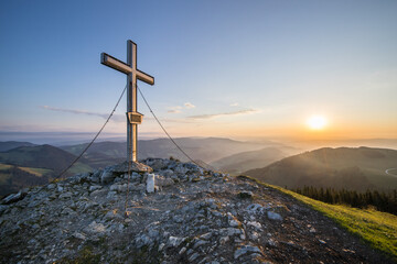 Fototapeta na wymiar The summit cross at the Plankogel in Styria, Austria on an early summer morning