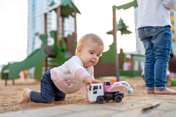 Toddler playing with toy car. Adorable little girl having fun on playground.