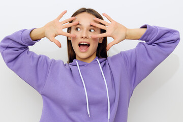 an admiring woman stands on a white background in a purple suit, happily looking forward, leaning her fingers against her face