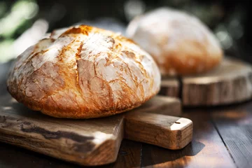 Foto op Plexiglas Bakkerij Traditional leavened sourdough bread with rought skin on a rustic wooden table. Healthy food photography