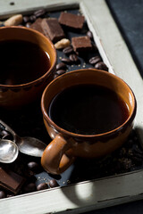 cups of black coffee, sugar and chocolate on a blackboard, top view closeup