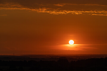 orange sunset in the summer on the background of the field