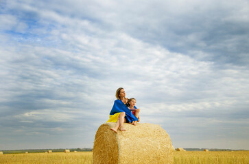 Child and mother with Ukrainian flag. A mother and child wrapped themselves in the Ukrainian...